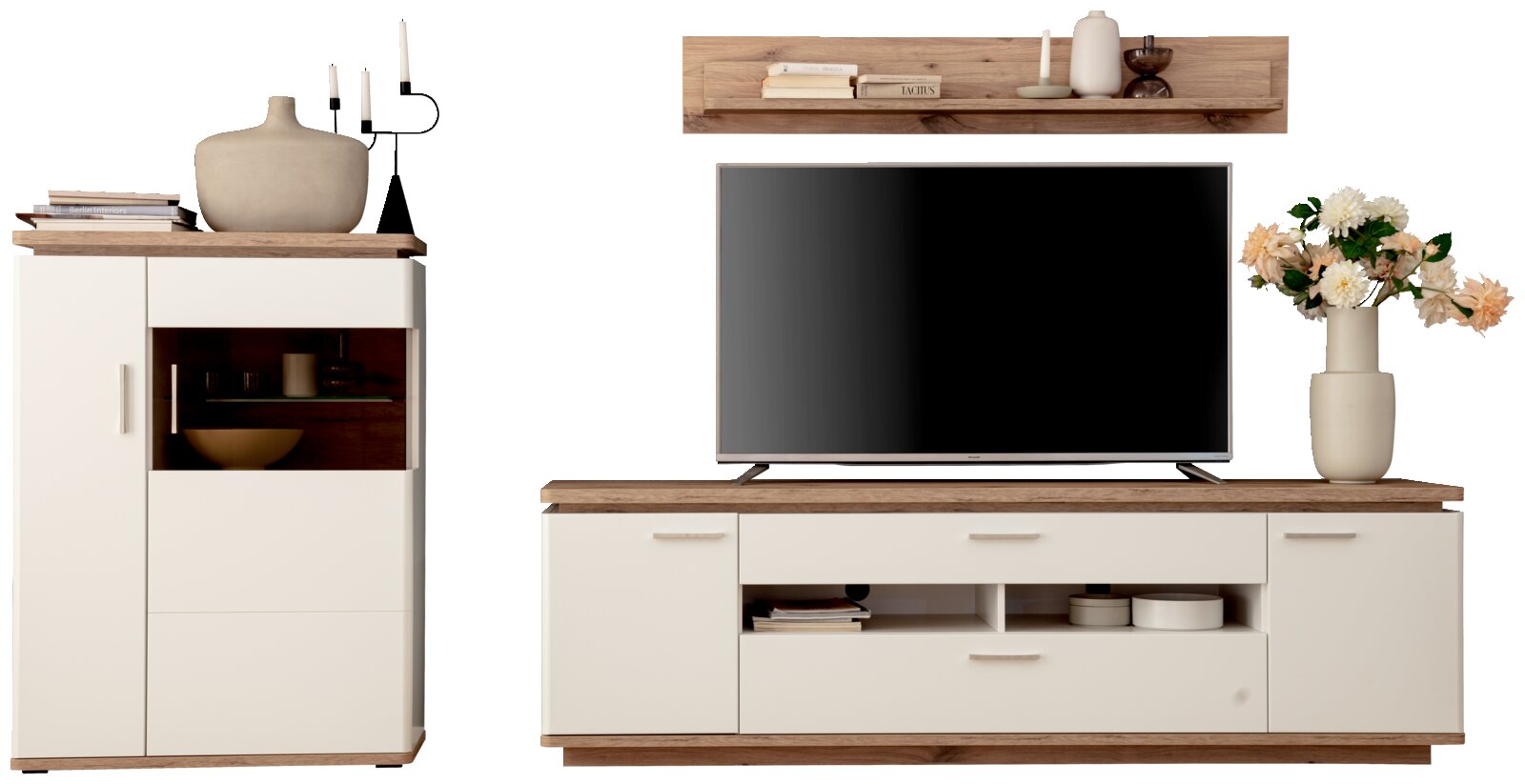 Frontansicht einer modernen Wohnwand im skandinavischen Stil: weißes Sideboard und Vitrine mit Holzoptik-Abdeckplatten, TV-Board mit Fernseher, Wandregal sowie Deko-Vasen und Blumen.