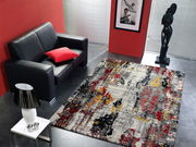 Moderner Designer Teppich in einem stilvollen Wohnzimmer mit schwarzem Ledersofa, rotem Kissen und Skulptur, aus der Vogelperspektive fotografiert.