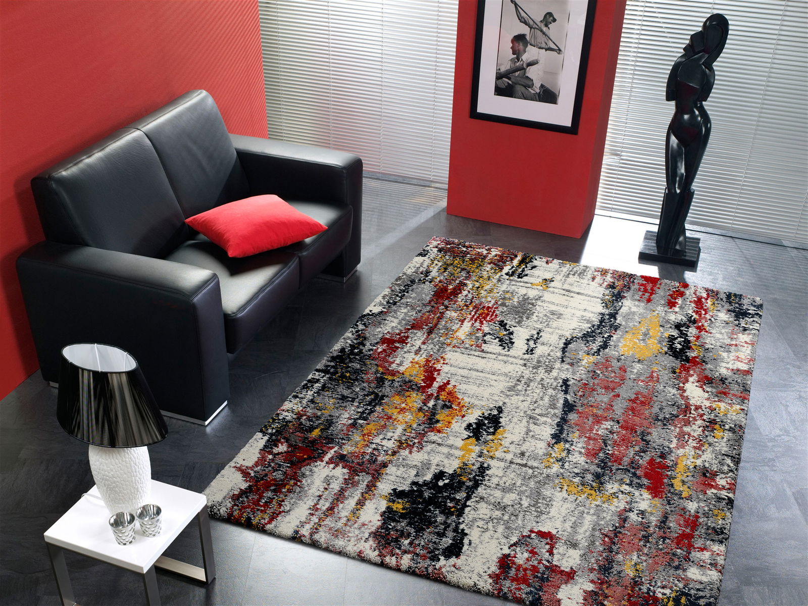 Moderner Designer Teppich in einem stilvollen Wohnzimmer mit schwarzem Ledersofa, rotem Kissen und Skulptur, aus der Vogelperspektive fotografiert.