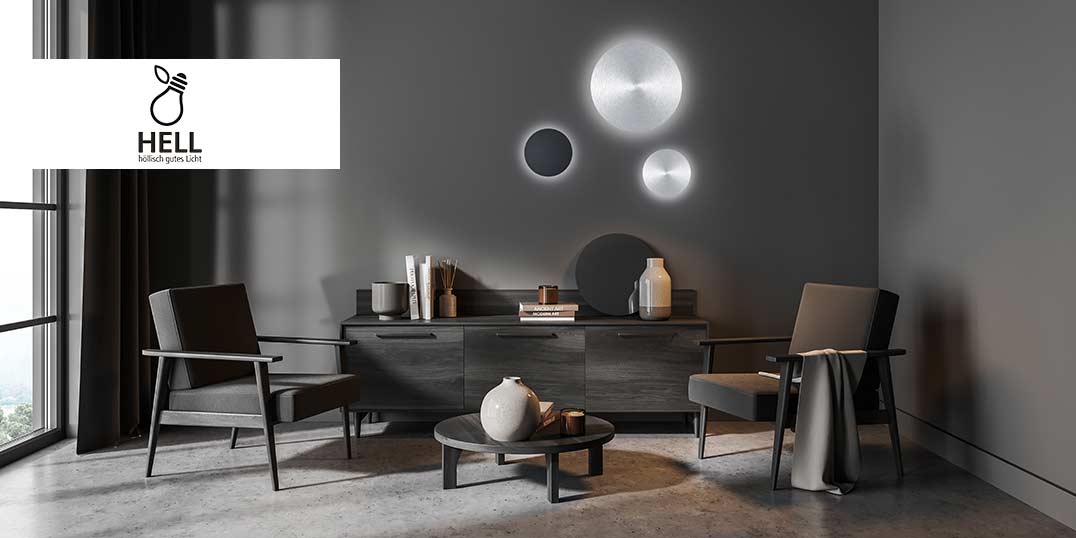 Een moderne woonkamer met twee donkere stoelen, een donker dressoir, decoratieve vazen en artistieke wandlampen tegen een donkergrijze muur.