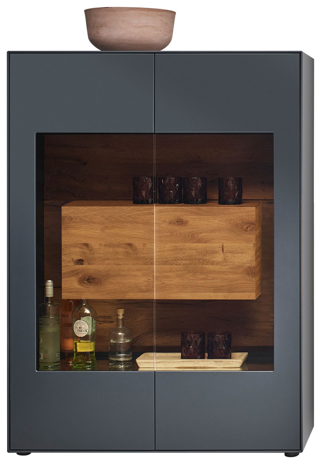 Frontansicht eines modernen Highboards mit Glasfront, dunklem Holzinterieur und dekorativen Gläsern und Flaschen.