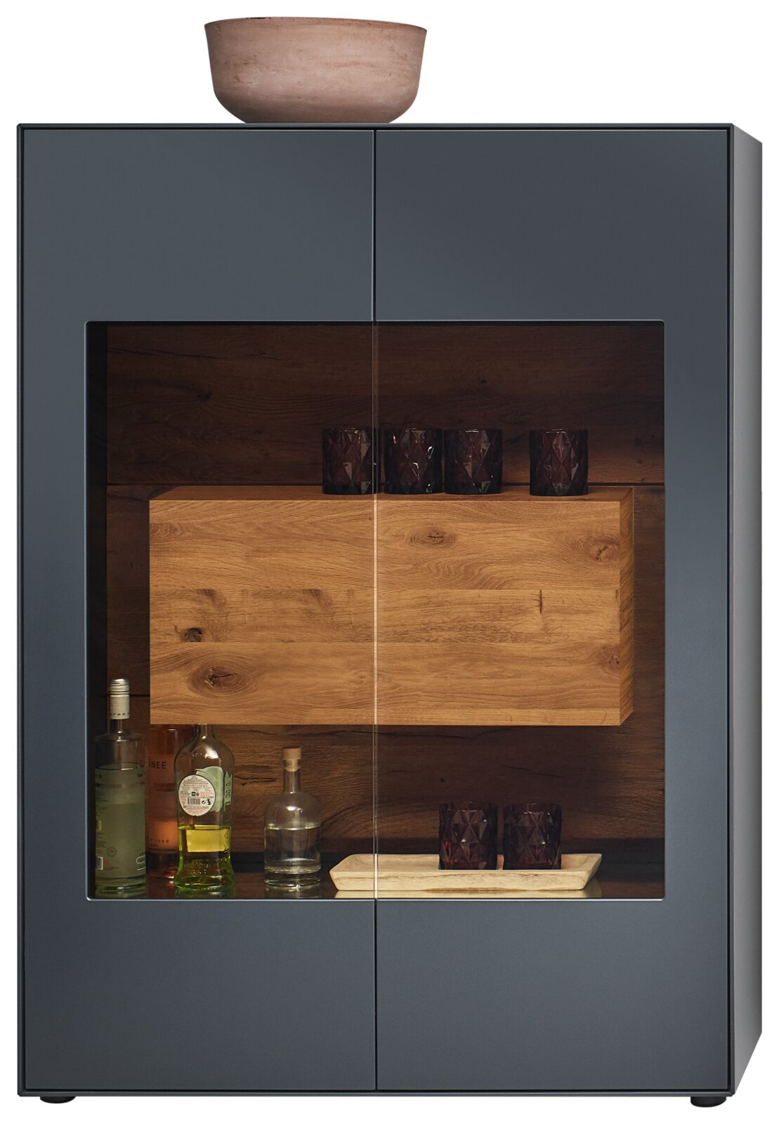 Frontansicht eines modernen Highboards mit Glasfront, dunklem Holzinterieur und dekorativen Gläsern und Flaschen.