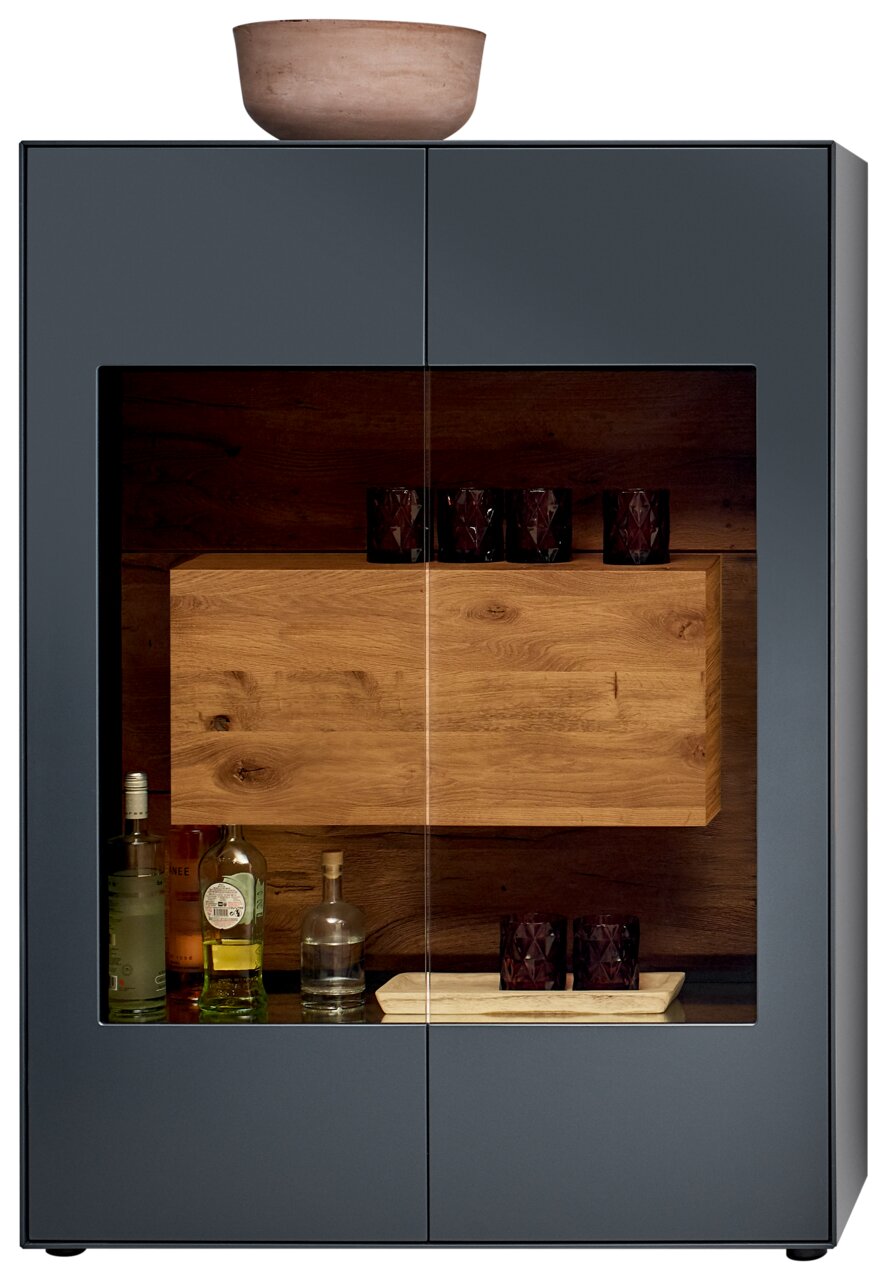 Frontansicht eines modernen Highboards mit Glasfront, dunklem Holzinterieur und dekorativen Gläsern und Flaschen.
