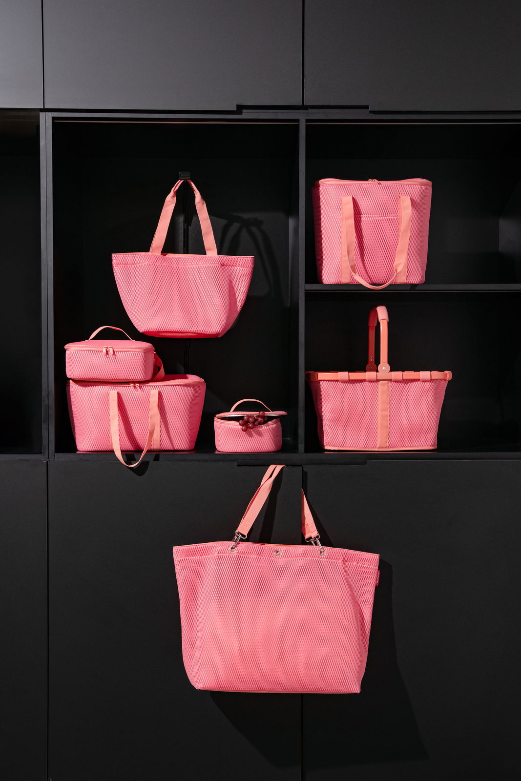 Verschiedene rosa Taschen in einem Regal, frontal betrachtet.