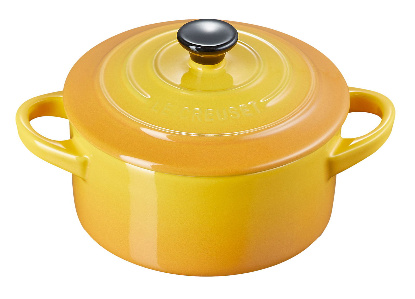 Gelbe Mini Cocotte von Le Creuset mit zwei Griffen und schwarzem Knauf, aus leicht erhöhter Perspektive