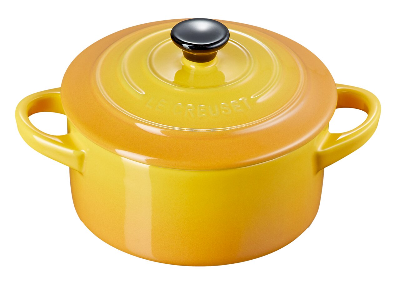 Gele mini-cocotte van Le Creuset met twee handvatten en een zwarte knop, vanuit een licht verhoogd perspectief