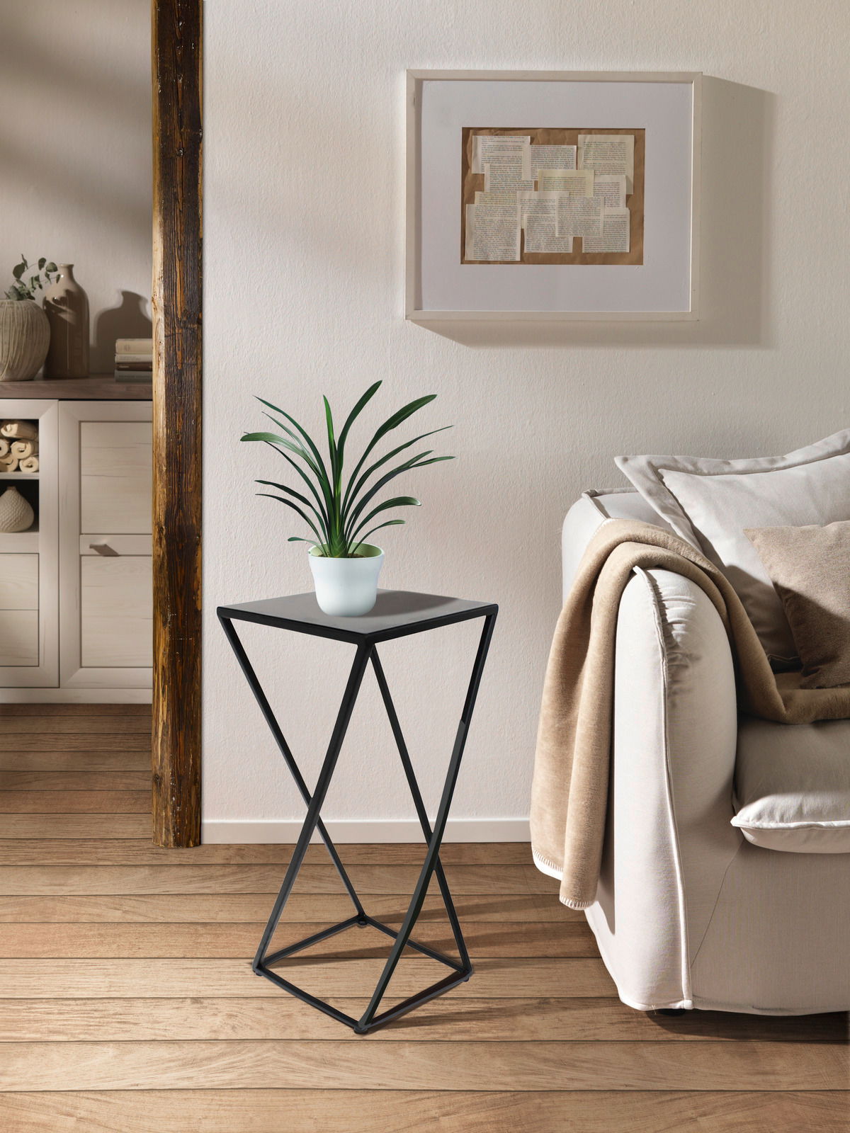 Moderner Beistelltisch mit schwarzem Metallgestell und quadratischer Platte, seitliche Perspektive, dekoriert mit einer Pflanze, in einem gemütlichen Wohnzimmer.