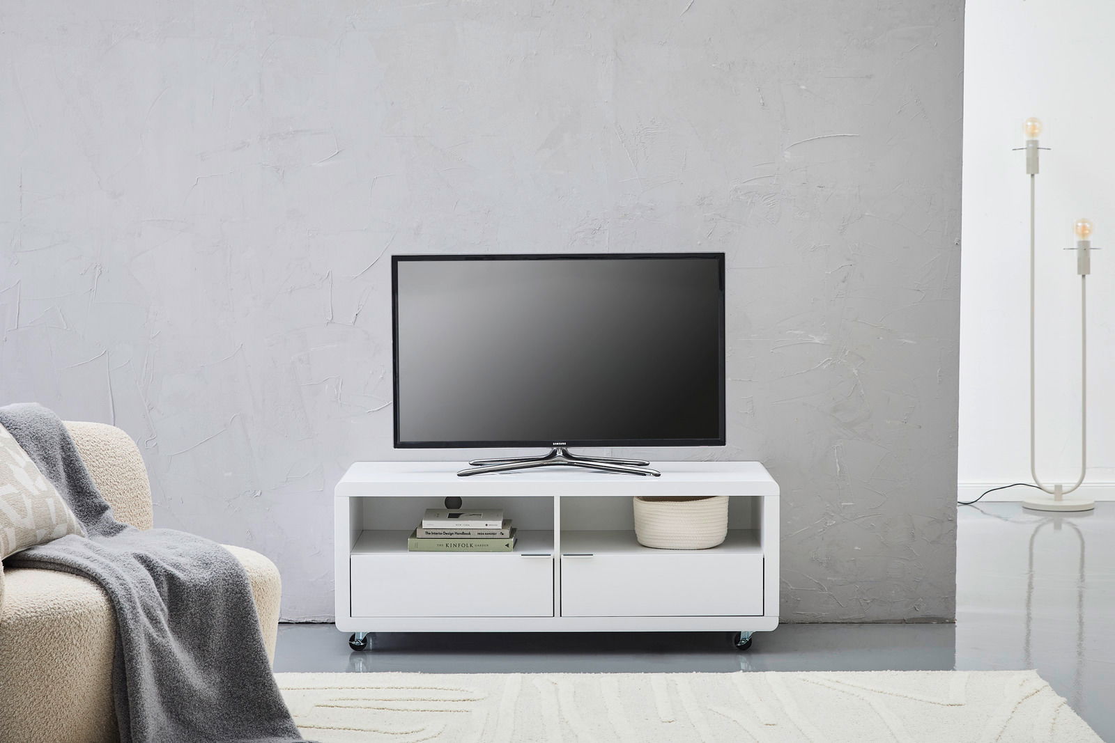 XORA TV-Lowboard LIMA Weißes TV-Lowboard mit zwei offenen Fächern und zwei Schubladen, darauf steht ein Flachbildfernseher, frontal fotografiert.