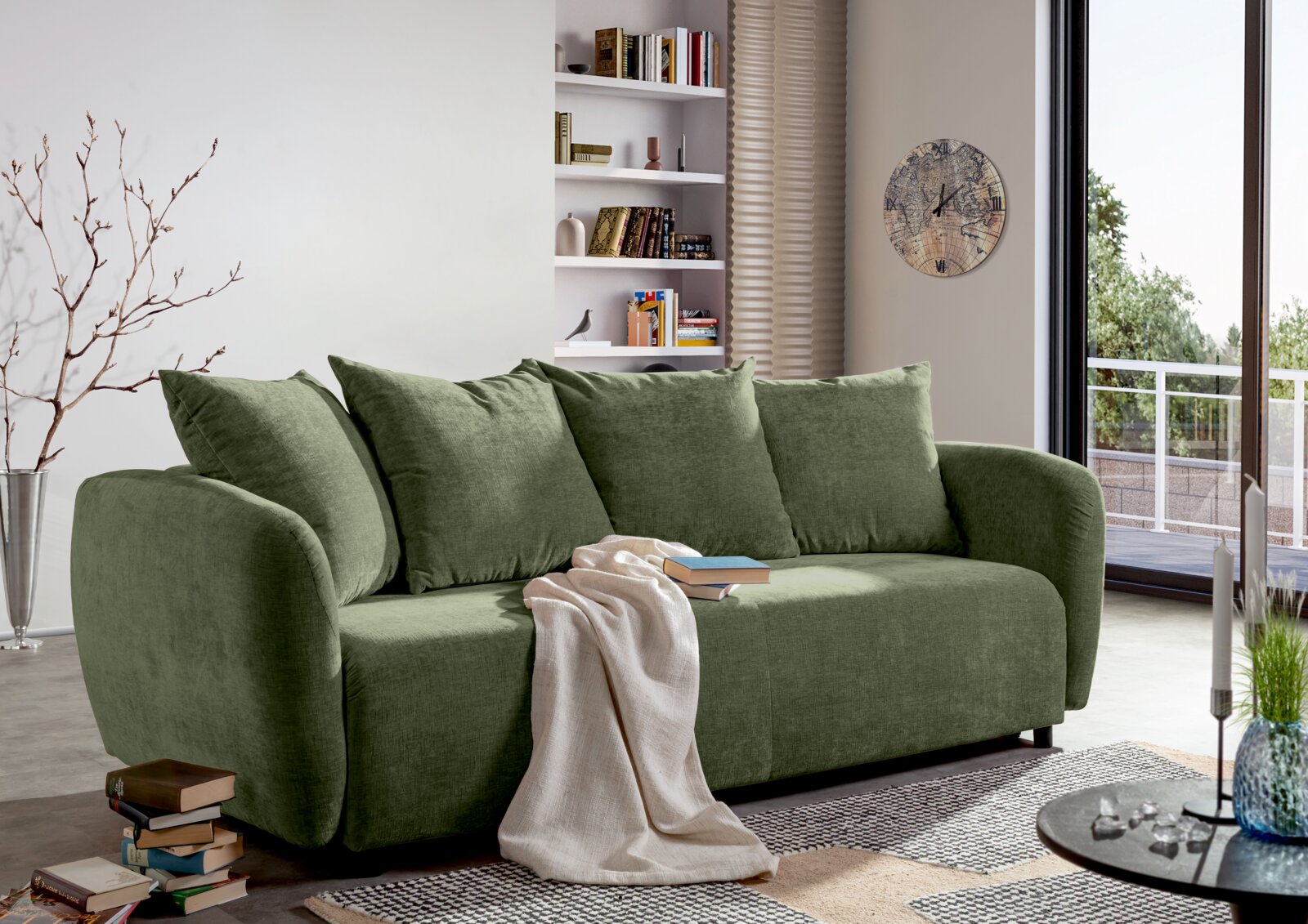 Groene functionele bank in een moderne woonkamer, gezien vanaf de zijkant, versierd met kussens en een deken.