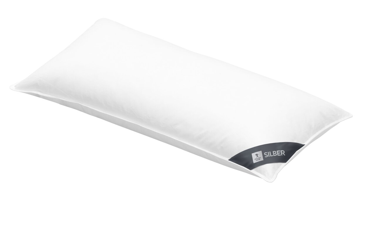 Weißes Kopfkissen 40x80cm in schräger Perspektive mit silbernem Etikett.