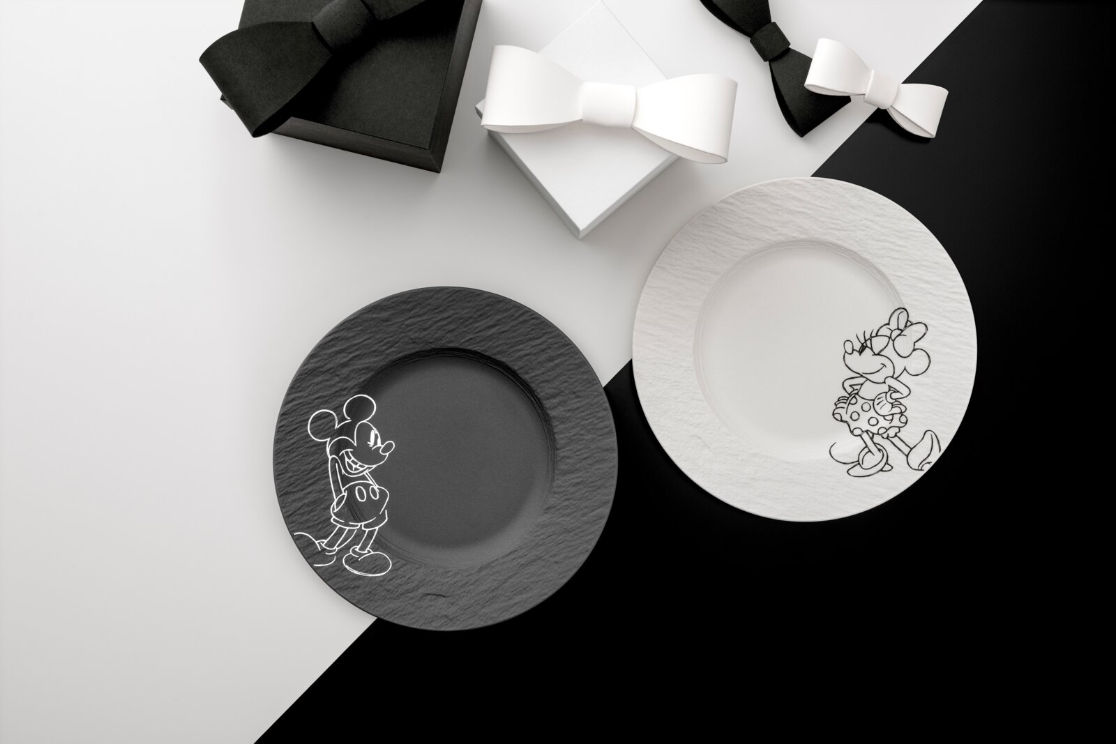 Villeroy & Boch Frühstücks-/Dessertteller 2-tlg. MICKEY MOUSE Draufsicht auf zwei dekorative Teller in Schwarz und Weiß mit skizzierten Mickey- und Minnie-Mouse-Motiven, arrangiert auf einem schwarz-weißen Hintergrund mit Geschenkboxen und Schleifen.