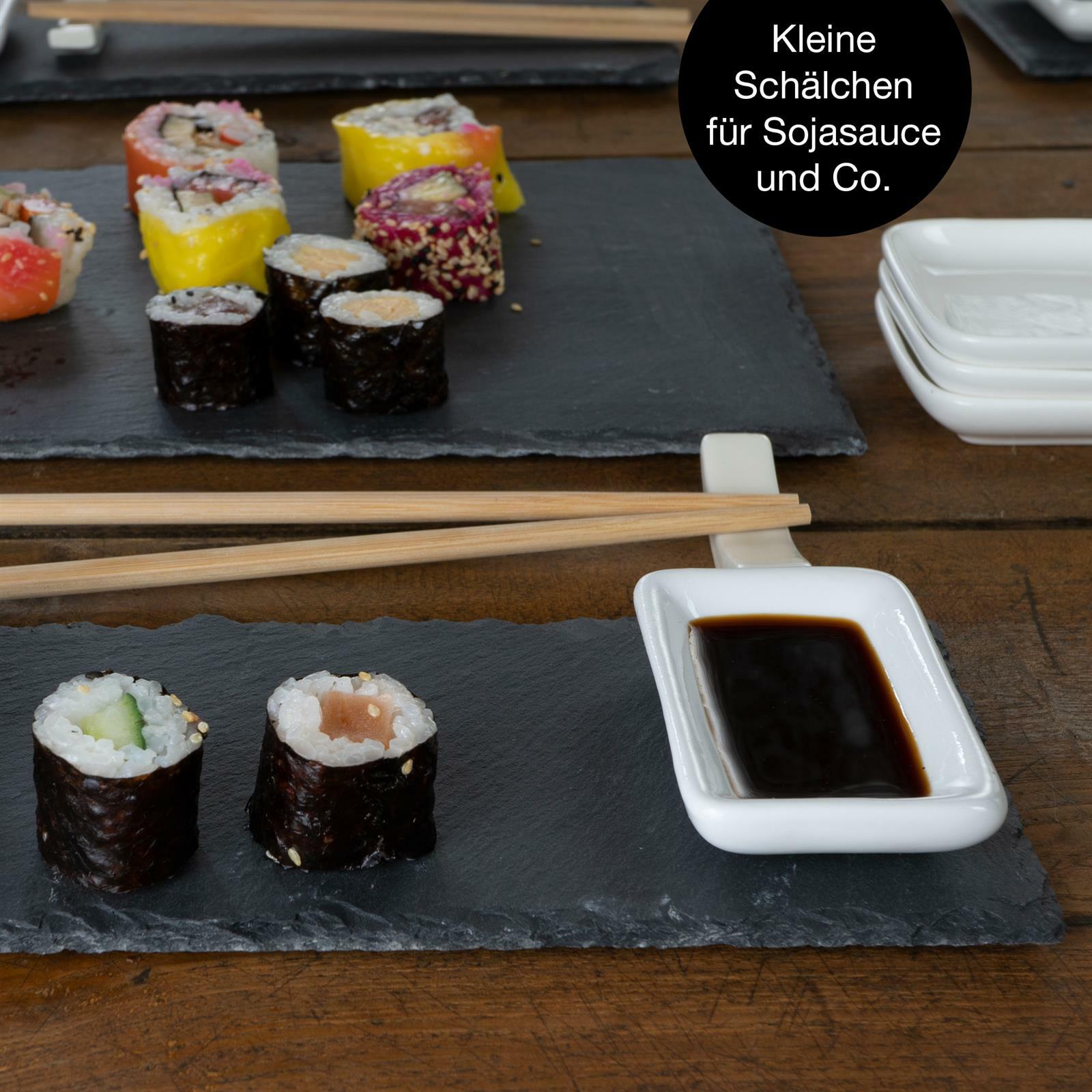 Sushi-Set auf Schieferplatte mit Sojasaucenschälchen und Essstäbchen, von oben fotografiert.