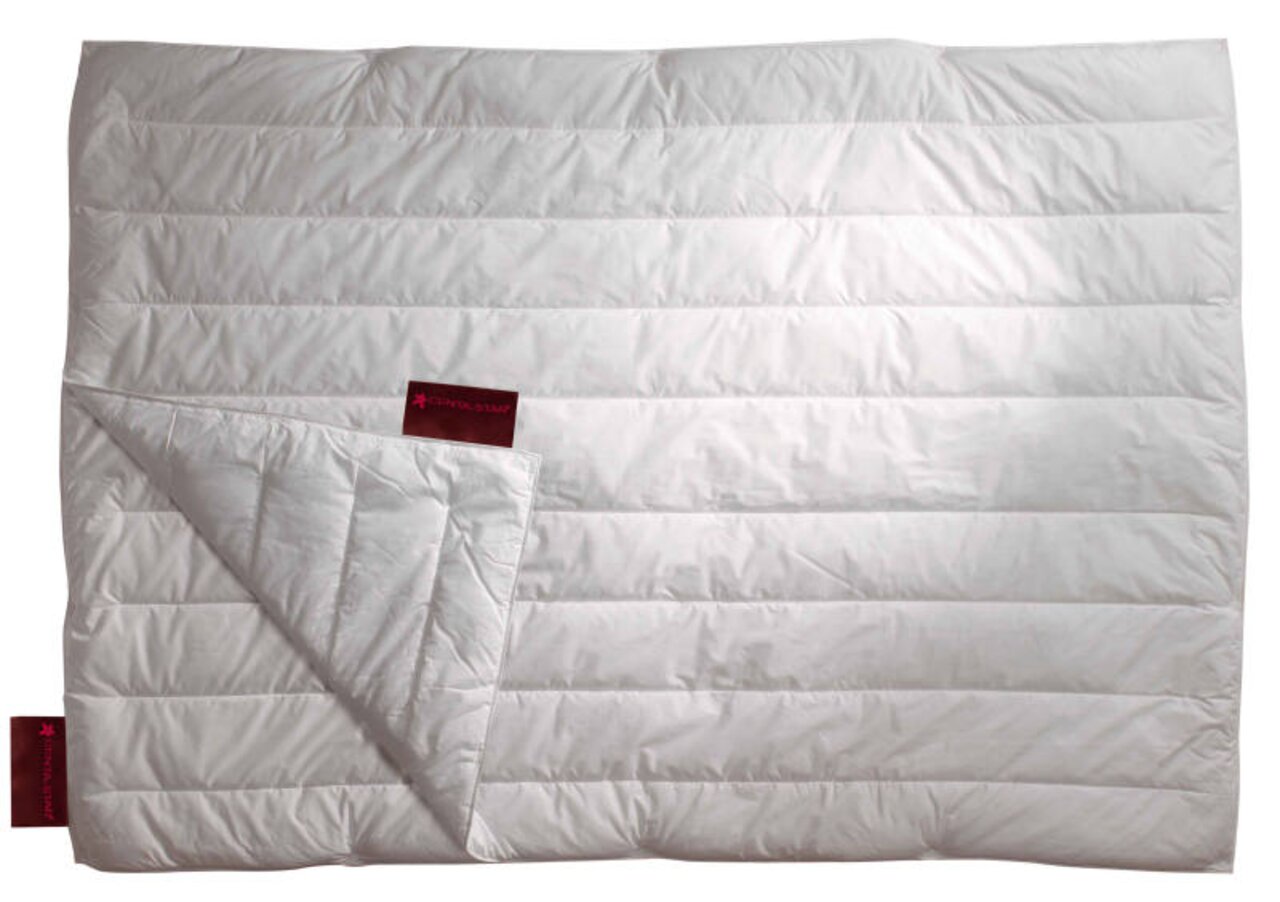 Weiße Bettdecke mit gestepptem Design, von oben betrachtet, mit einer Ecke umgeschlagen, um die Innenseite zu zeigen.