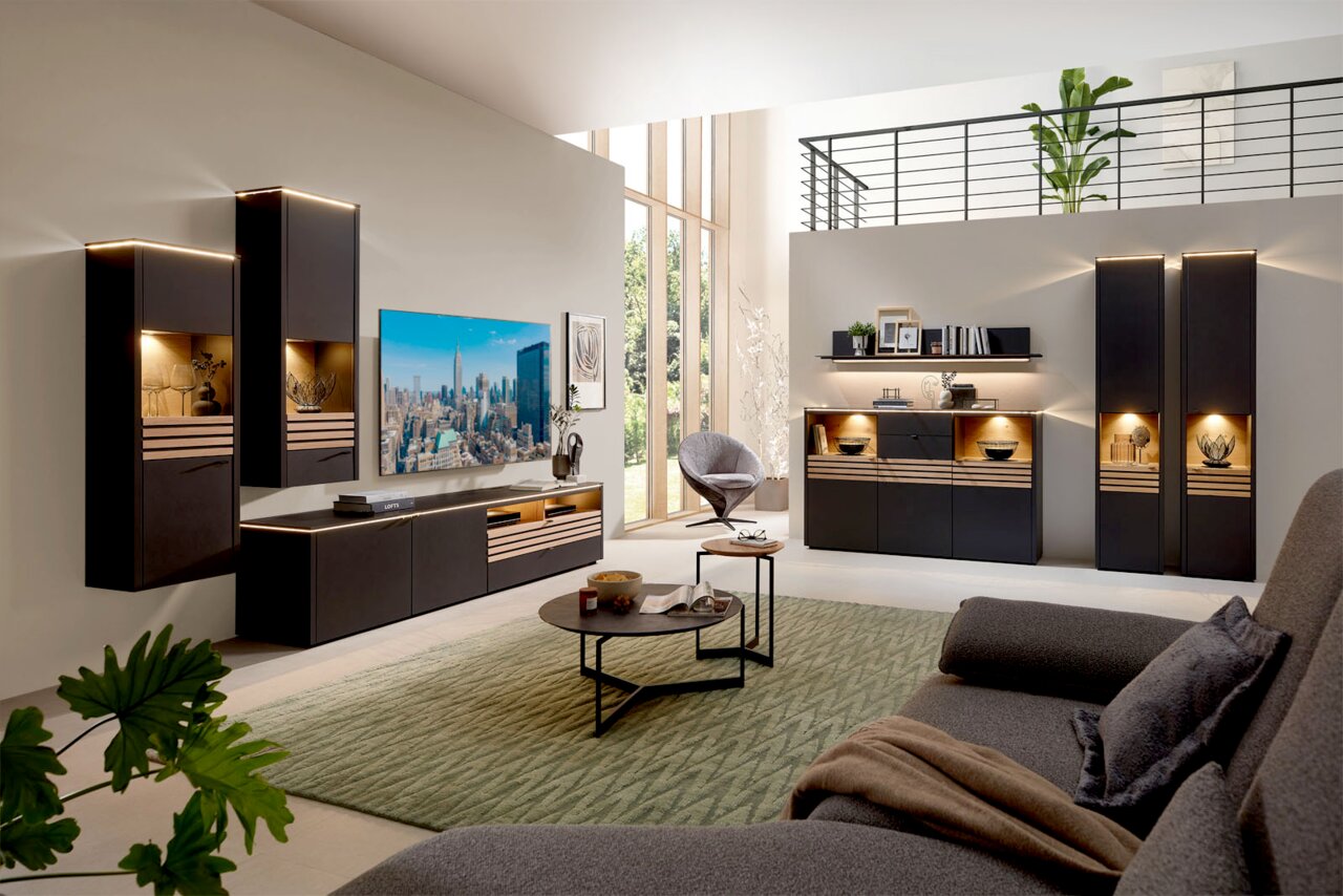 Venjakob Beistelltisch Moderne Wohnzimmermöbel mit LED-Beleuchtung, bestehend aus Hängeschränken, einem TV-Board und einem Couchtisch, aus der Perspektive eines gemütlichen Wohnzimmers mit Blick auf eine große Fensterfront.