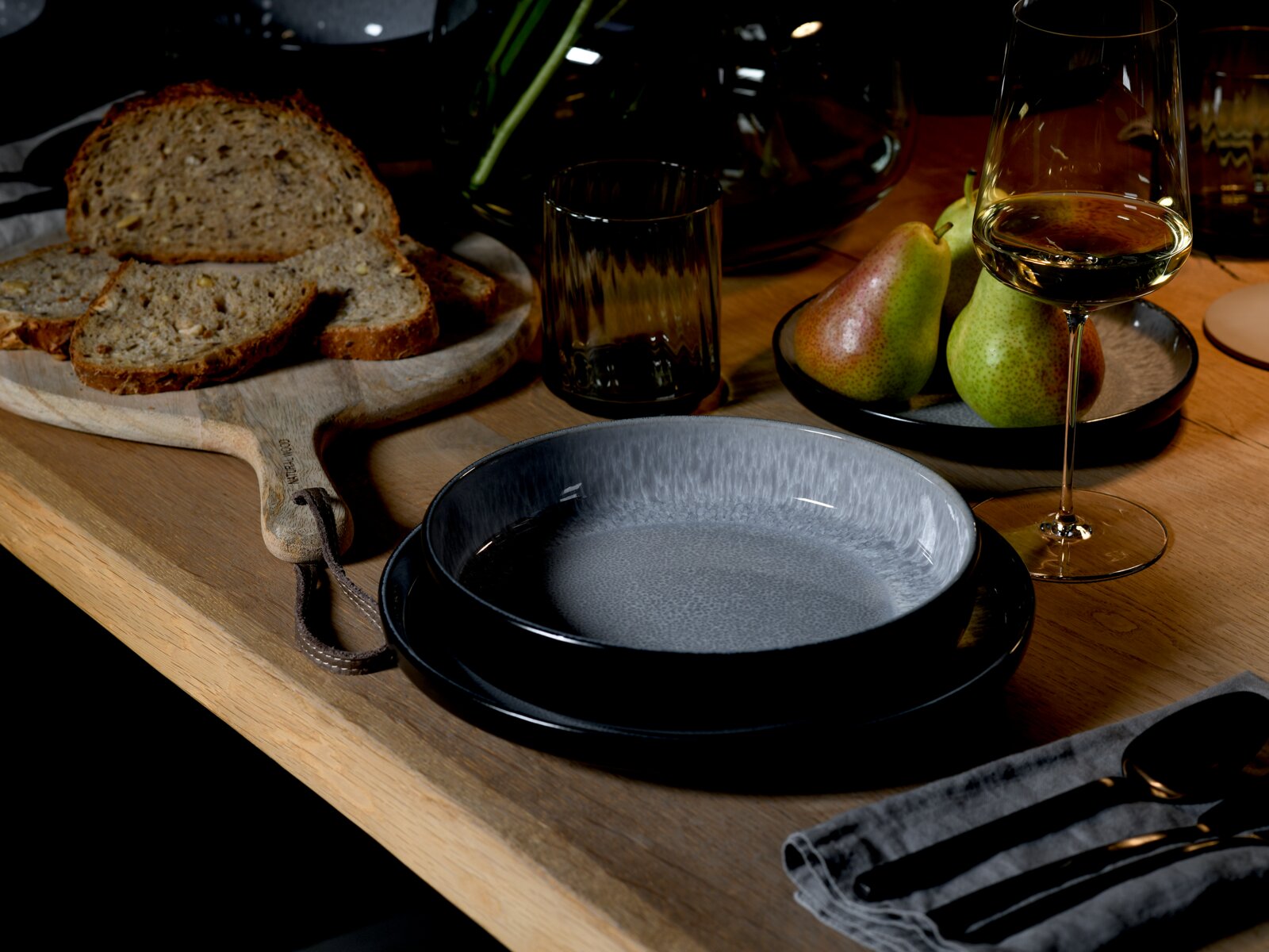 Elegantes Tafelservice in moderner Tischdekoration mit Brotscheiben, Birnen und einem Glas Weißwein, seitliche Perspektive