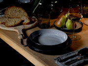 Elegantes Tafelservice in moderner Tischdekoration mit Brotscheiben, Birnen und einem Glas Weißwein, seitliche Perspektive