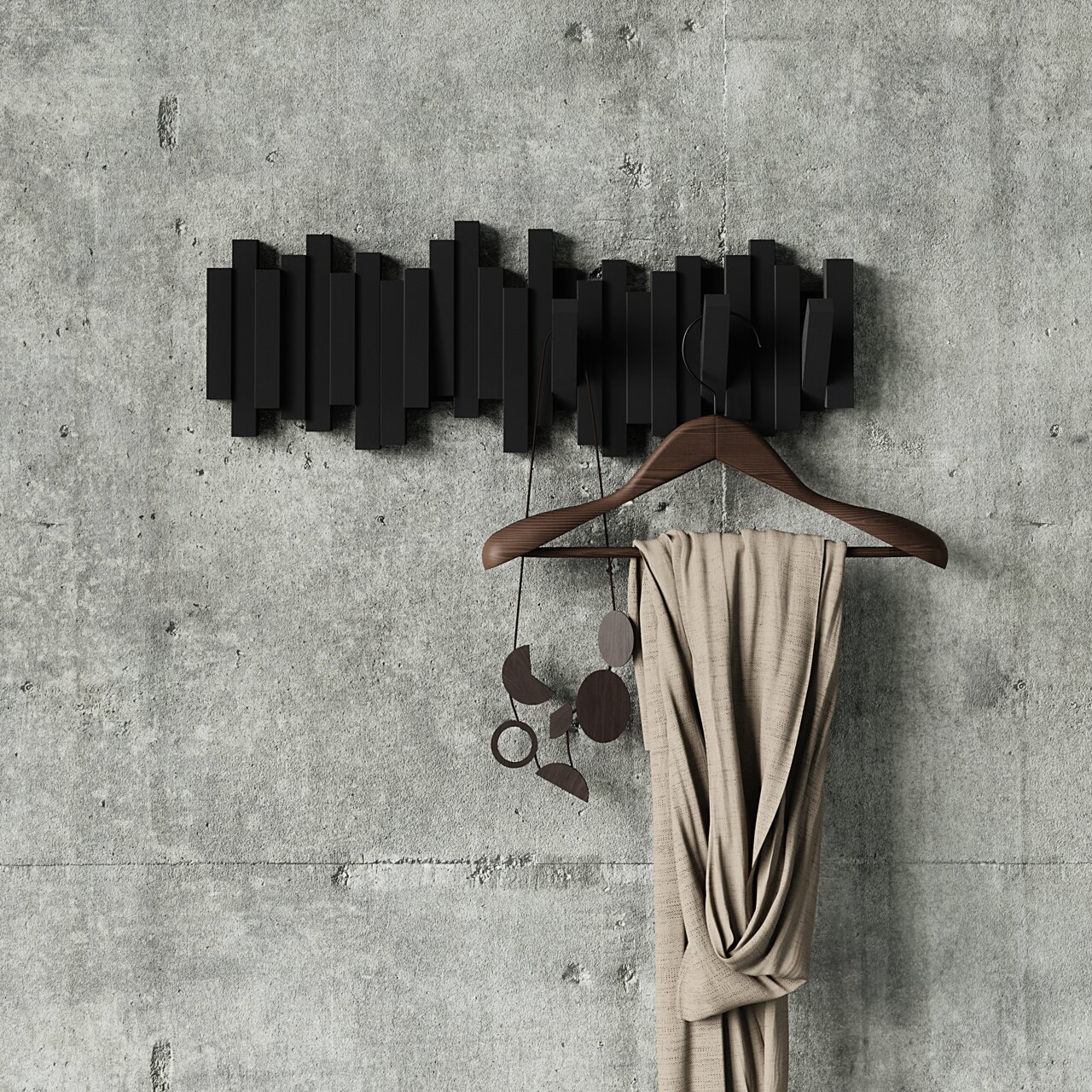 Moderne schwarze Wandgarderobe mit geometrischem Design, frontal an einer Betonwand montiert, mit einem Kleiderbügel und einem Schal dekoriert.