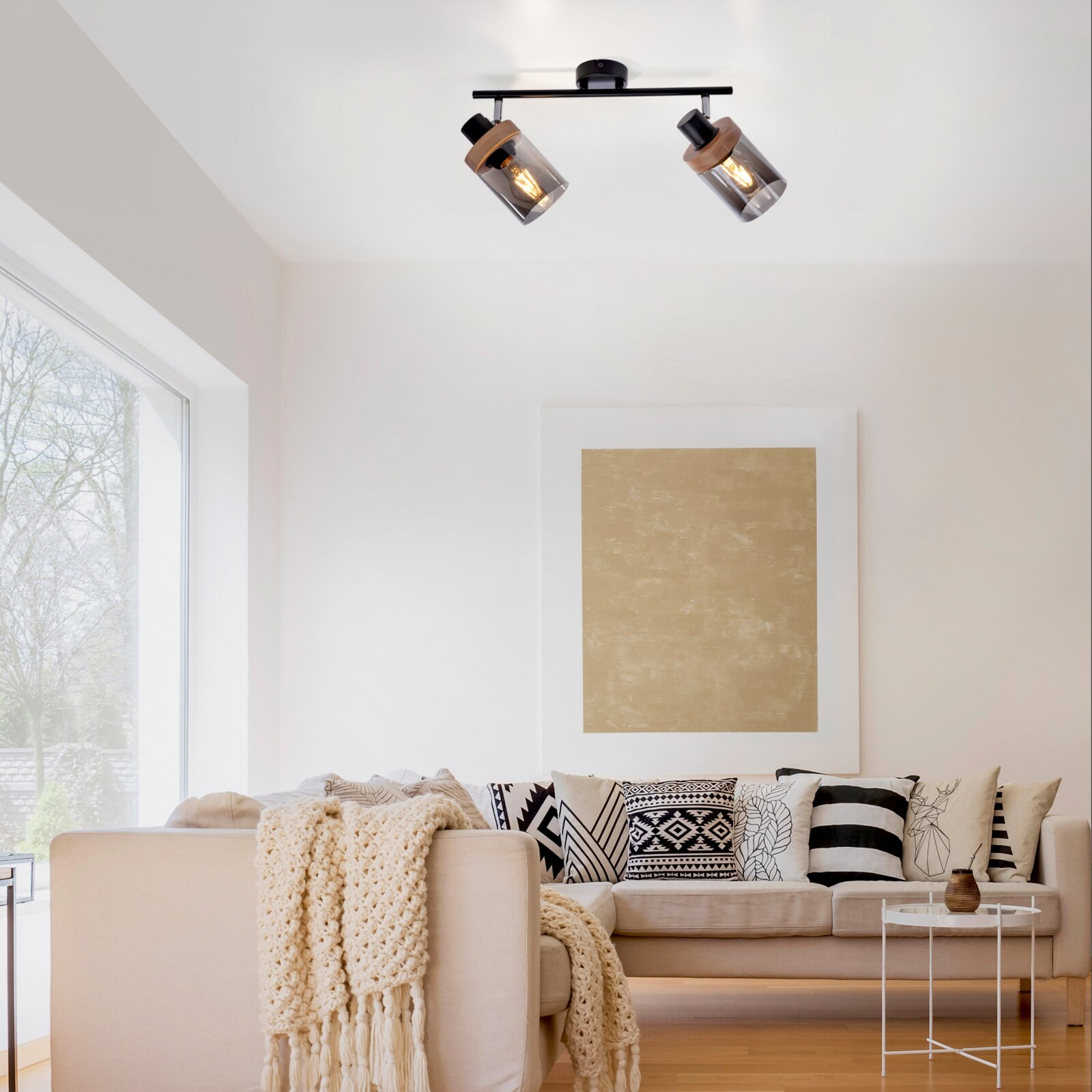 Moderne 2-flammige Deckenleuchte/Spotleuchte in Schwarz mit Rauchglas-Schirmen und Holzdetails, eingeschaltet, in einem hellen Wohnzimmer – Perspektive: leicht von unten nach oben auf die Deckenmontage