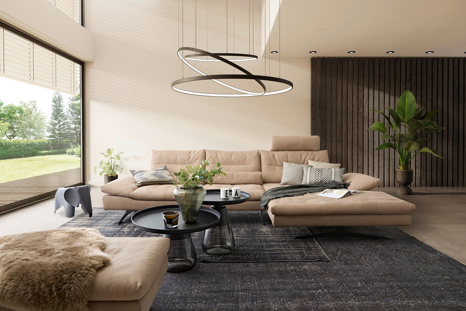 Moderne Longchairkombination in einem eleganten Wohnzimmer mit großen Fenstern, die einen Blick auf den Garten bieten. Die Perspektive zeigt die Longchairkombination von vorne, umgeben von stilvollen Dekorationen und Pflanzen.