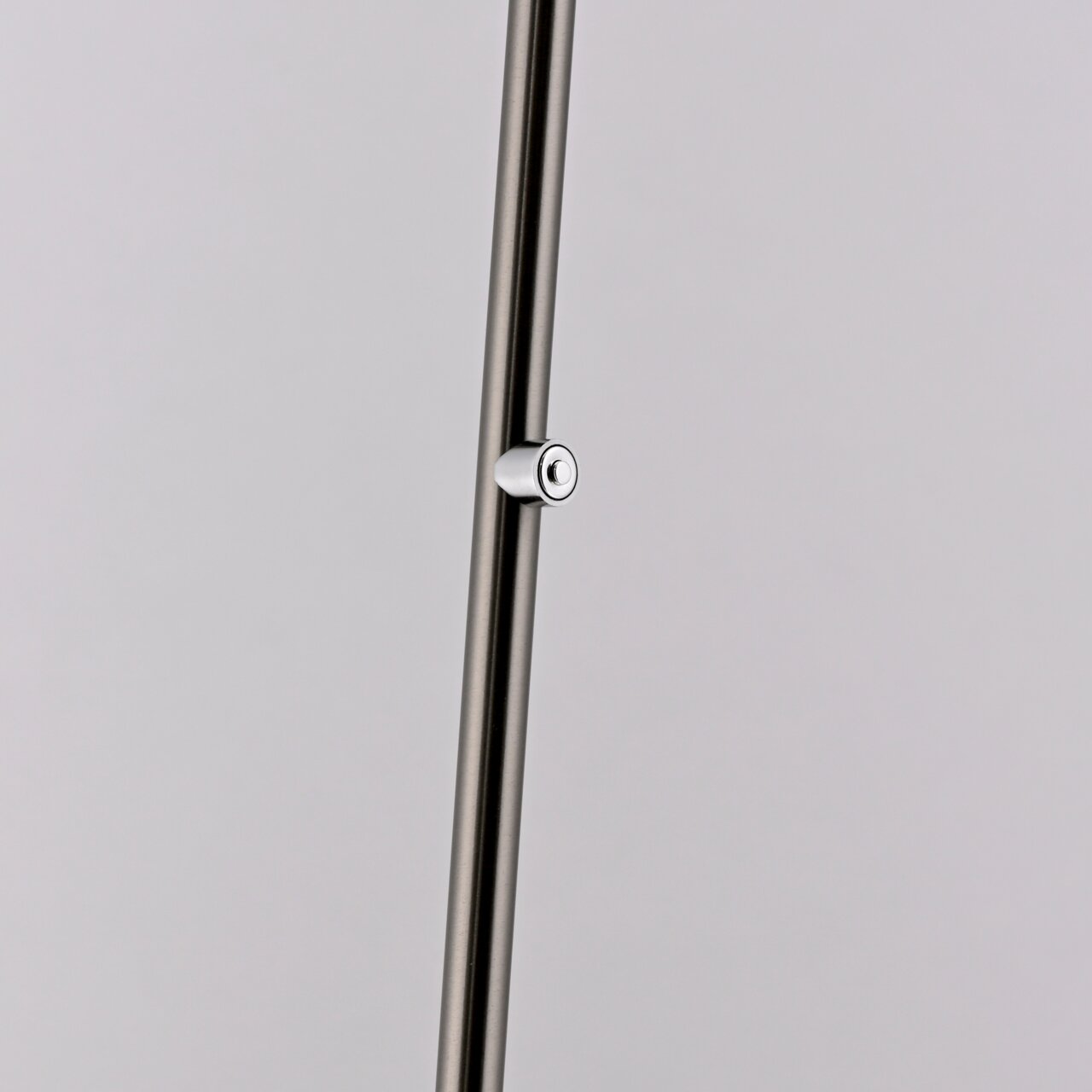 Nahaufnahme eines schlanken, metallischen Stabs mit einem kleinen, runden Schalter, Teil der Akku-Stehleuchte BENTE.