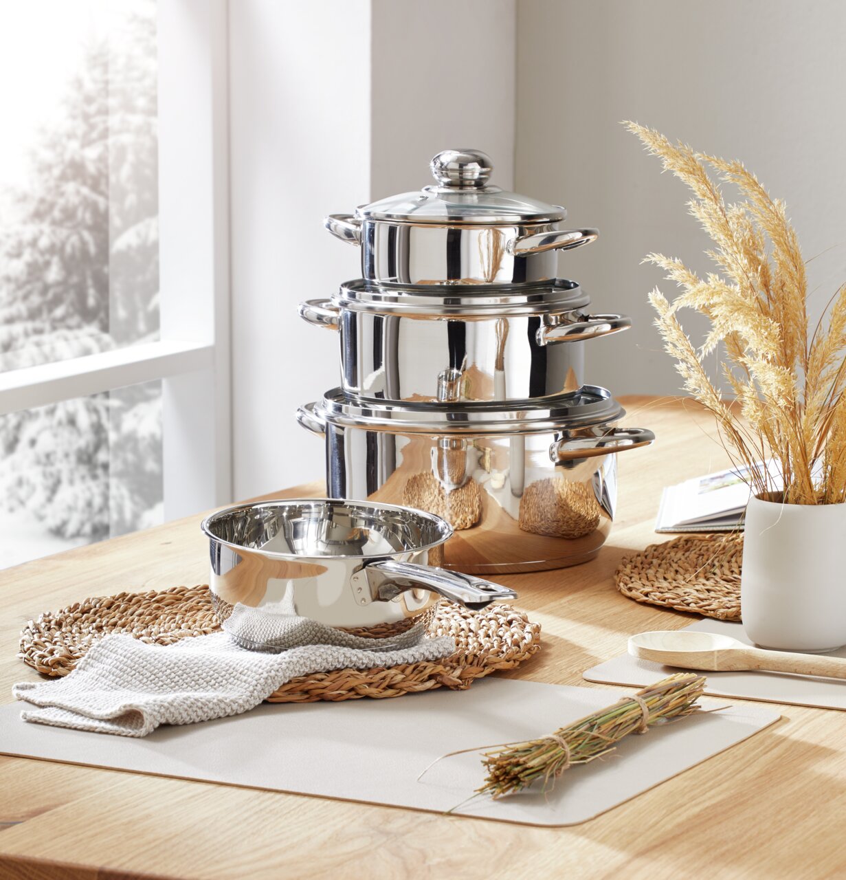 Edelstahl Kochtopfset, 4-teilig, auf einem Holztisch arrangiert, seitliche Perspektive