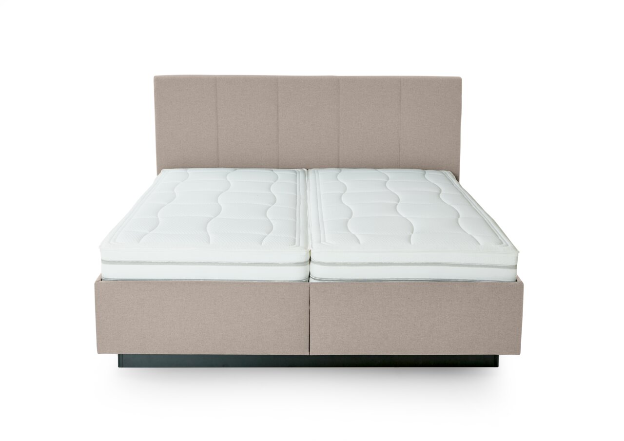 Vooraanzicht van een gestoffeerd bed met twee witte matrassen en een gestoffeerd hoofdeinde in beige.