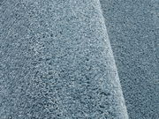 Nahaufnahme eines blauen Uni-Teppichs mit weicher, flauschiger Textur, seitliche Perspektive.