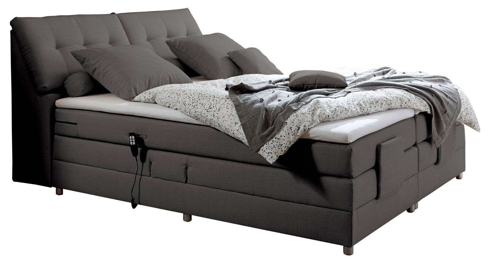 Graues Boxspringbett mit verstellbarem Kopfteil, mehreren Kissen und einer gemusterten Bettdecke, seitliche Perspektive