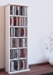 Schmales, weißes CD-Regal mit mehreren Ablagefächern, gefüllt mit CDs, freistehend auf Holzfußboden vor heller Wand; Perspektive: frontale Ansicht mit leichter Schrägansicht von links.