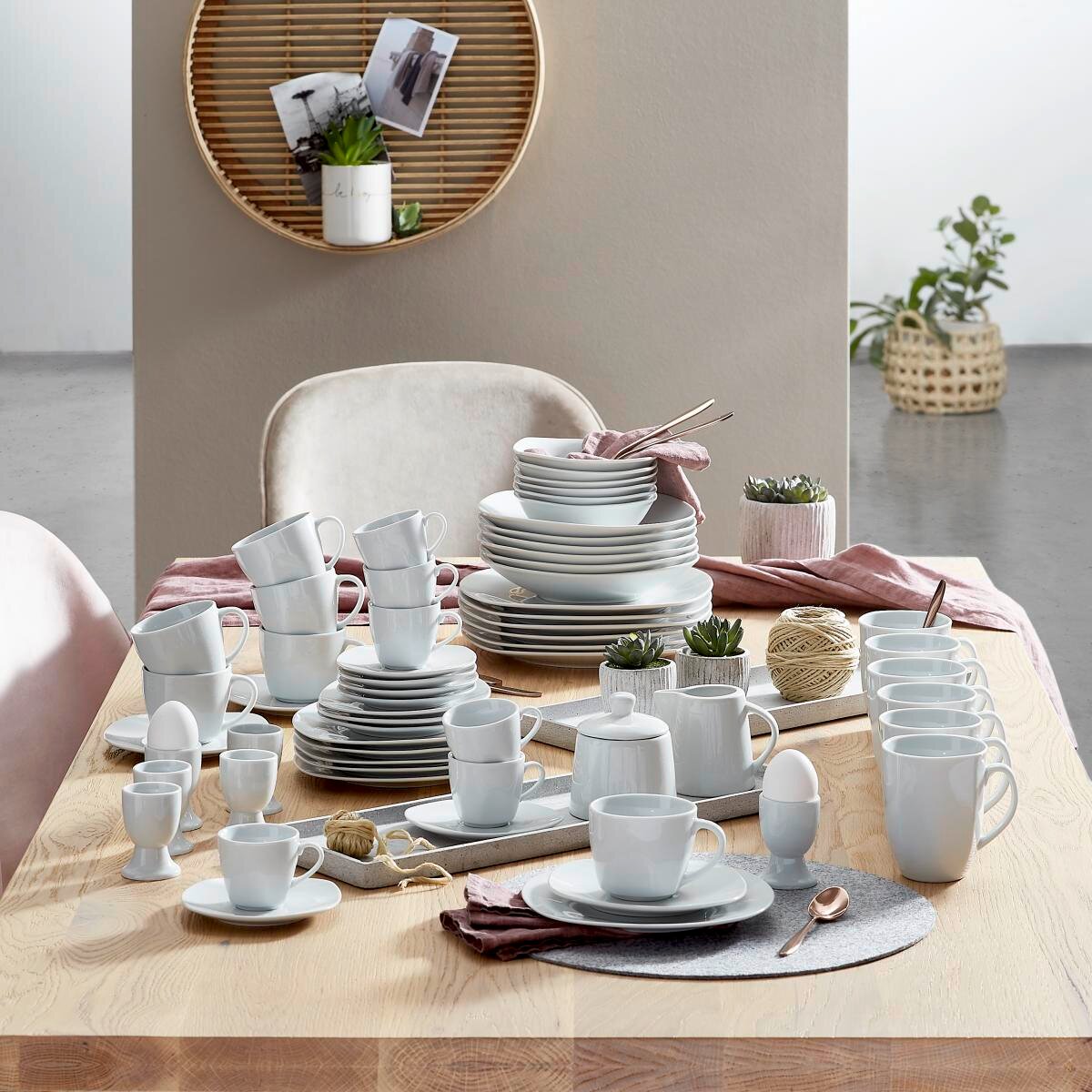 Een elegant 62-delig servies in wit op een gedekte tafel, gefotografeerd vanuit een zijaanzicht.