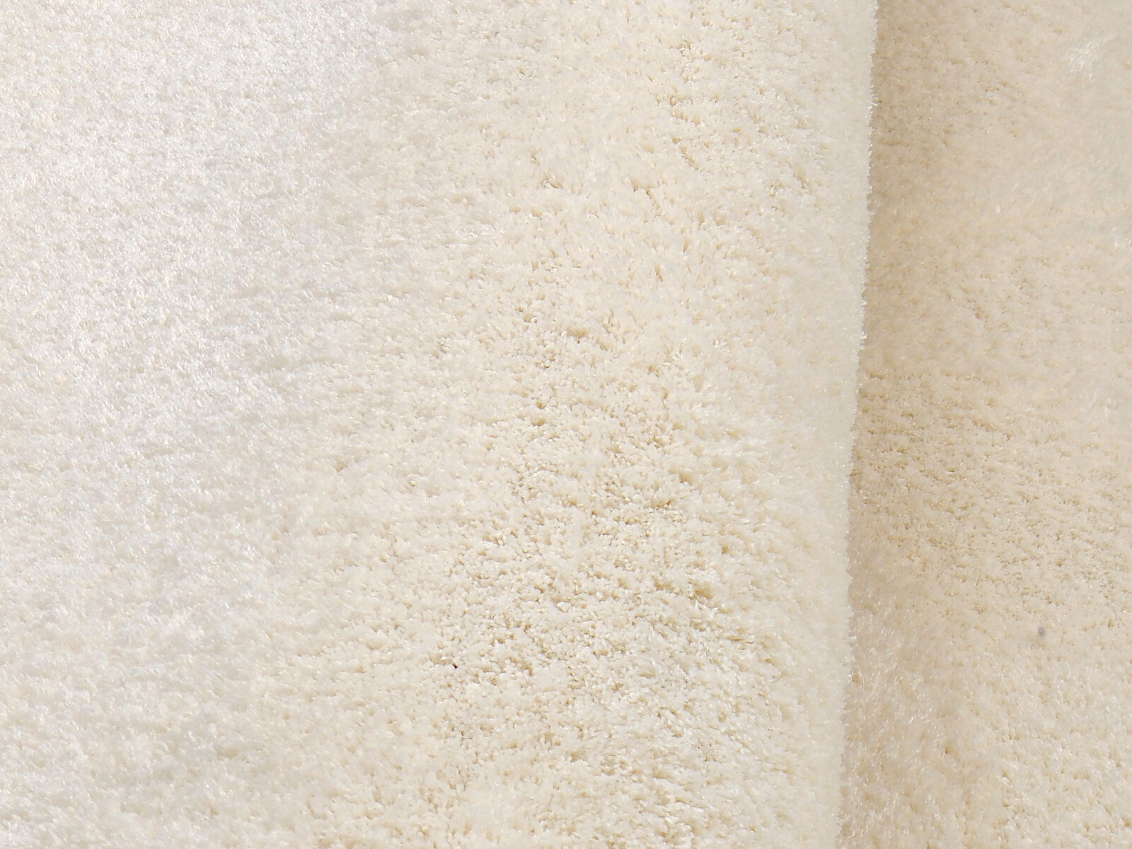 Nahaufnahme eines weichen, cremefarbenen Teppichs mit flauschiger Textur.