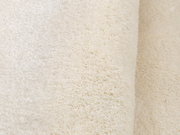 Nahaufnahme eines weichen, cremefarbenen Teppichs mit flauschiger Textur.