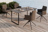Vier Loungesessel um einen rechteckigen Tisch auf einer Terrasse mit Blick auf das Wasser, seitliche Perspektive.