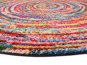 Bunte Nahaufnahme eines runden Hochflor-Teppichs mit spiralförmigem Muster aus verschiedenen Farben.