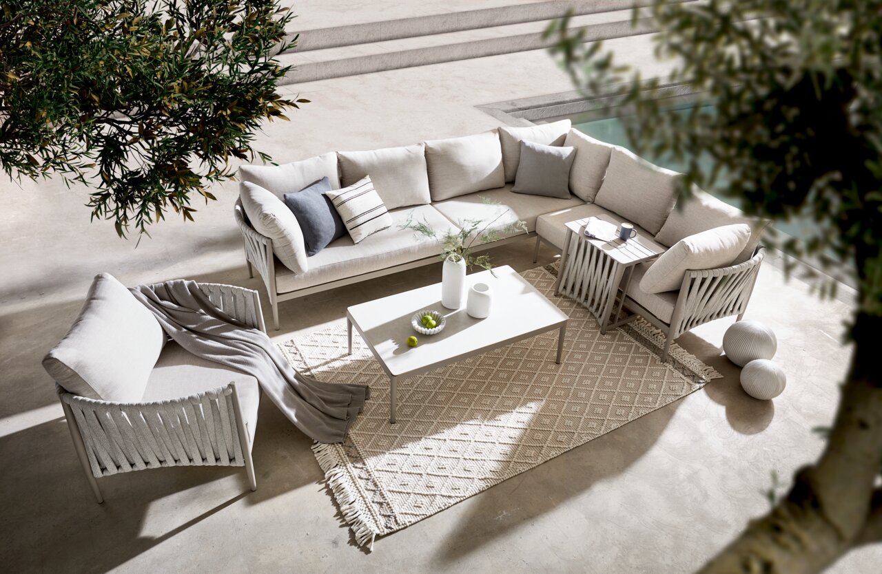 Loungetisch in moderner Outdoor-Lounge mit beigen Sofas und Kissen, von oben fotografiert.