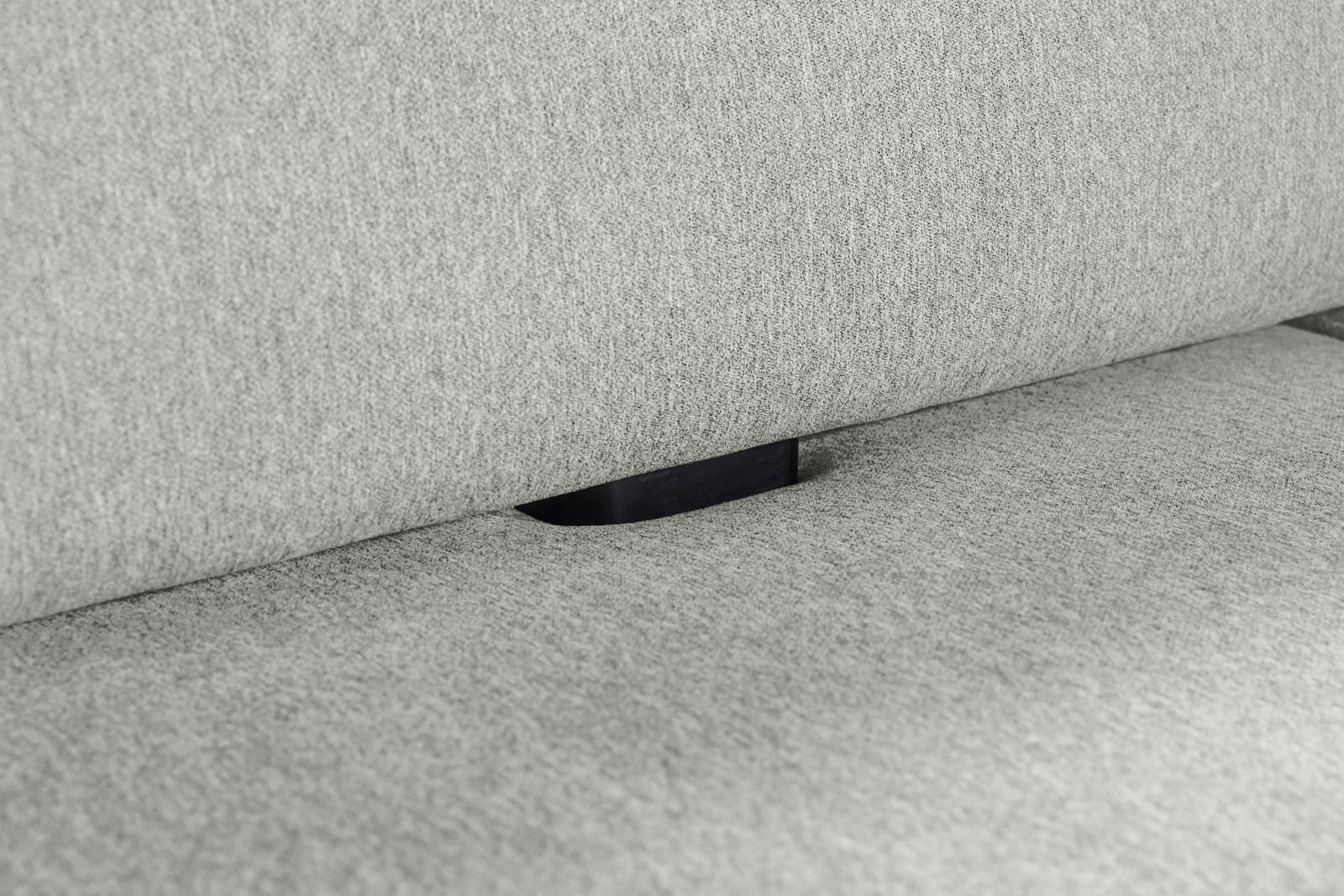 Nahaufnahme einer grauen Polsterung mit einem schwarzen Verbindungselement zwischen Sitzfläche und Rückenlehne.