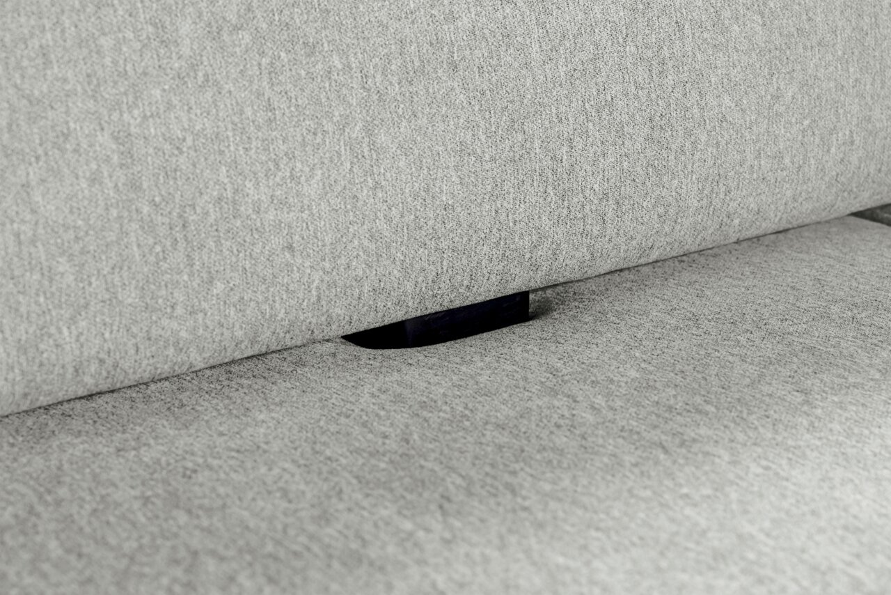 Nahaufnahme einer grauen Polsterung mit einem schwarzen Verbindungselement zwischen Sitzfläche und Rückenlehne.