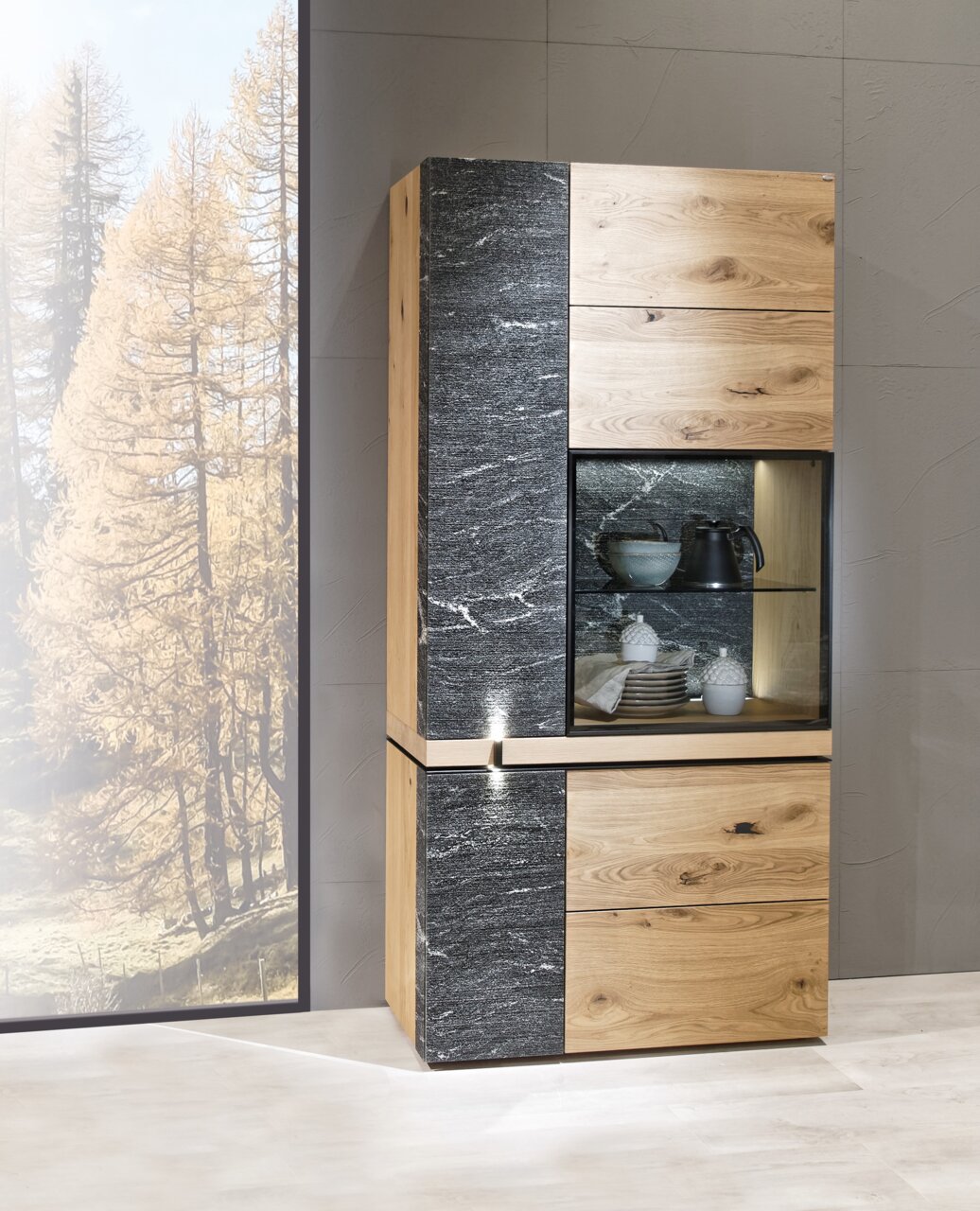 Vitrine Voglauer V-ROCK aus Holz und Steinoptik, frontal fotografiert, mit Glaseinsatz und Beleuchtung.