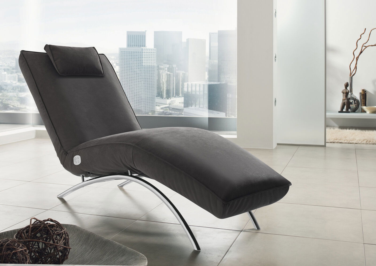 Koinor Liege JONAS Moderne schwarze Liege mit gebogenem Metallgestell in einem hellen Raum mit Stadtblick, seitliche Perspektive
