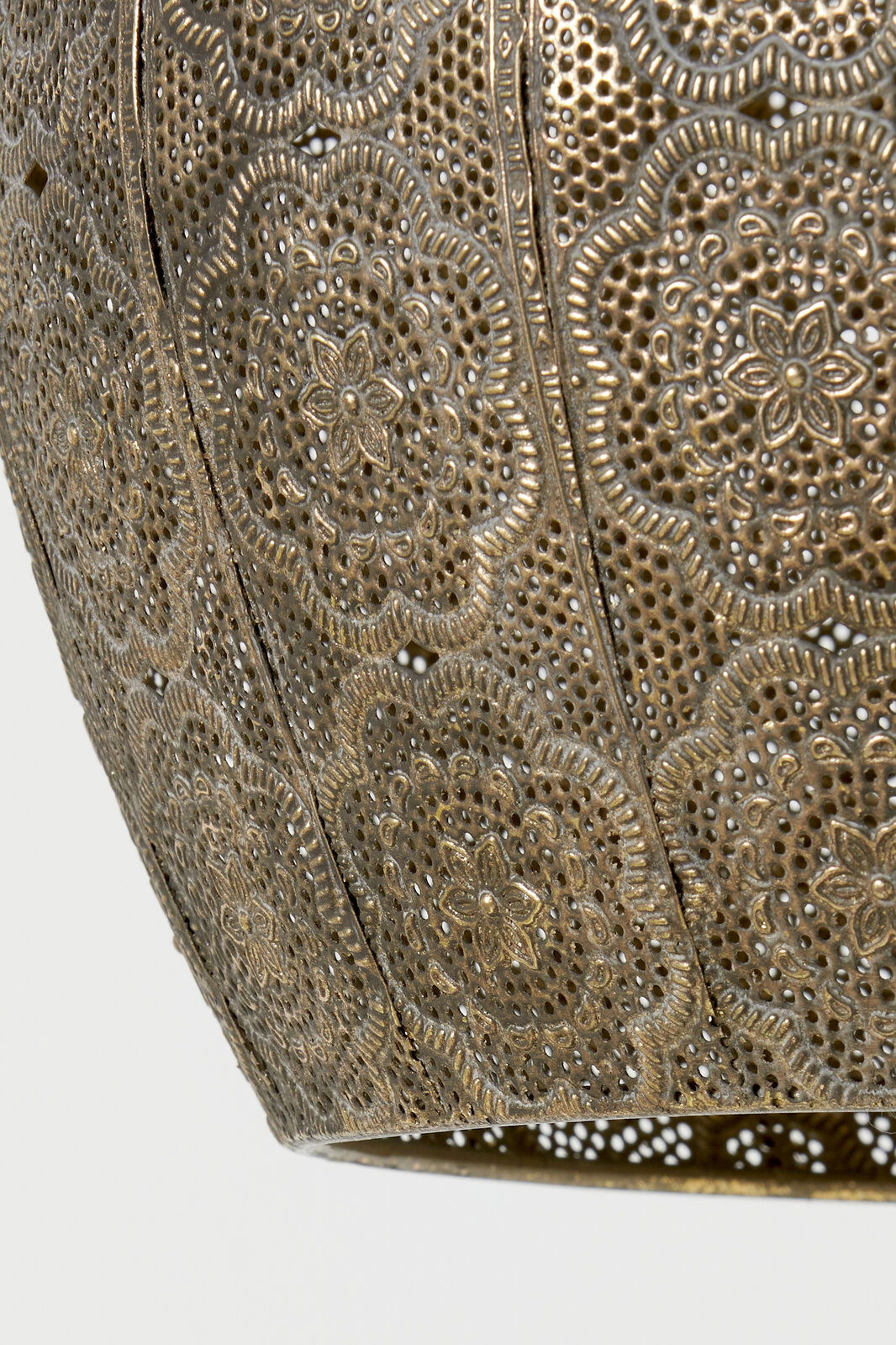 Detailansicht einer kunstvoll verzierten Hängeleuchte mit filigranem Muster in goldener Farbe.