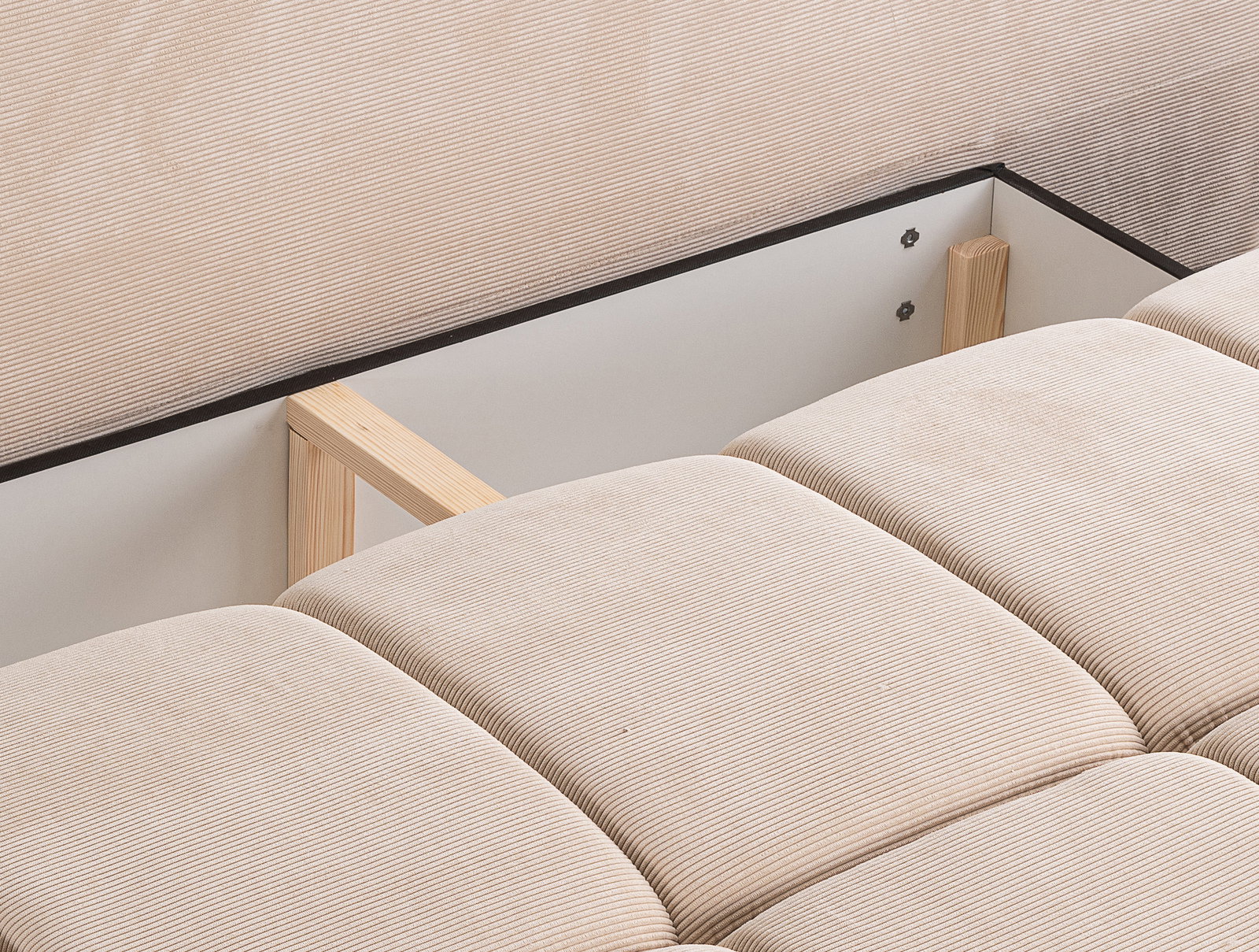 Nahaufnahme eines Schlafsofas mit beigem Stoffbezug und sichtbarer Holzstruktur, Perspektive von oben.