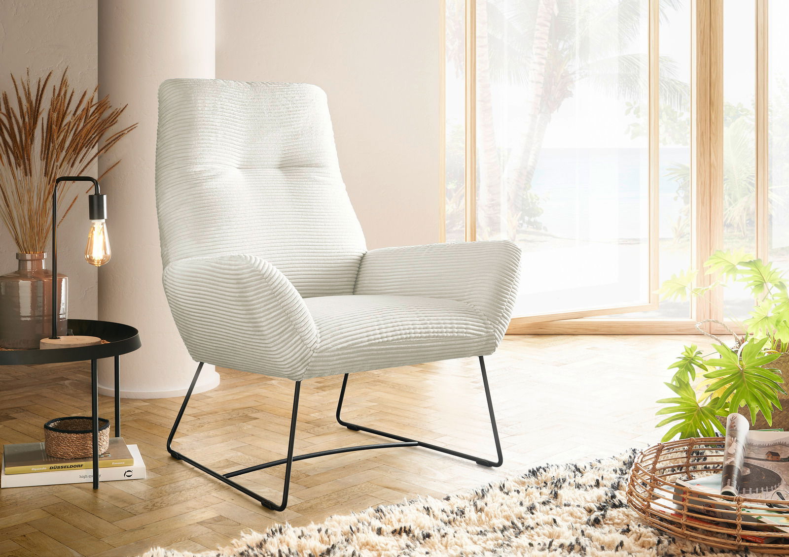 Lounge Handmade Sessel LH-BEN Moderner Sessel mit hellgrauem Stoffbezug und schwarzen Metallbeinen, seitliche Perspektive in einem hellen Raum mit großen Fenstern.