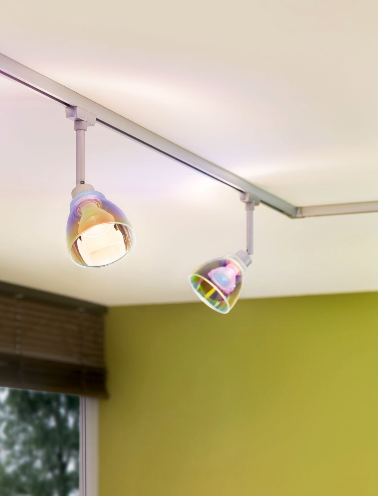 Zwei moderne Deckenstrahler mit bunten Glasschirmen, montiert an einer Schiene an der Decke, seitliche Perspektive.