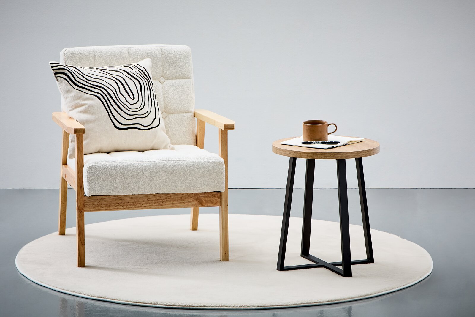 Moderner Beistelltisch mit runder Holzplatte und schwarzen Metallbeinen, seitliche Perspektive.