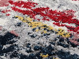 Nahaufnahme eines Designer-Teppichs mit buntem, strukturiertem Muster in Rot, Gelb, Blau und Weiß aus seitlicher Perspektive.