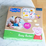Esslernteller und Würfel mit Peppa Pig Design, organisch und bio-zirkulär, in einer Verpackung mit fröhlichem Kind, aus der Vogelperspektive.