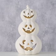 Weißer Teelichthalter in Form von drei gestapelten Kürbissen mit geschnitzten Gesichtern, frontal betrachtet.