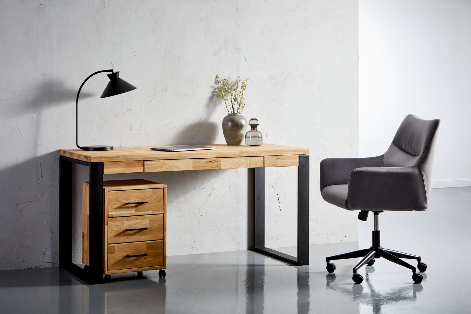 Linea Natura Schreibtisch MARCO Moderner Schreibtisch aus Holz mit schwarzem Metallgestell, linksseitig mit drei Schubladen, dekoriert mit einer Tischlampe und Vasen, seitliche Perspektive.