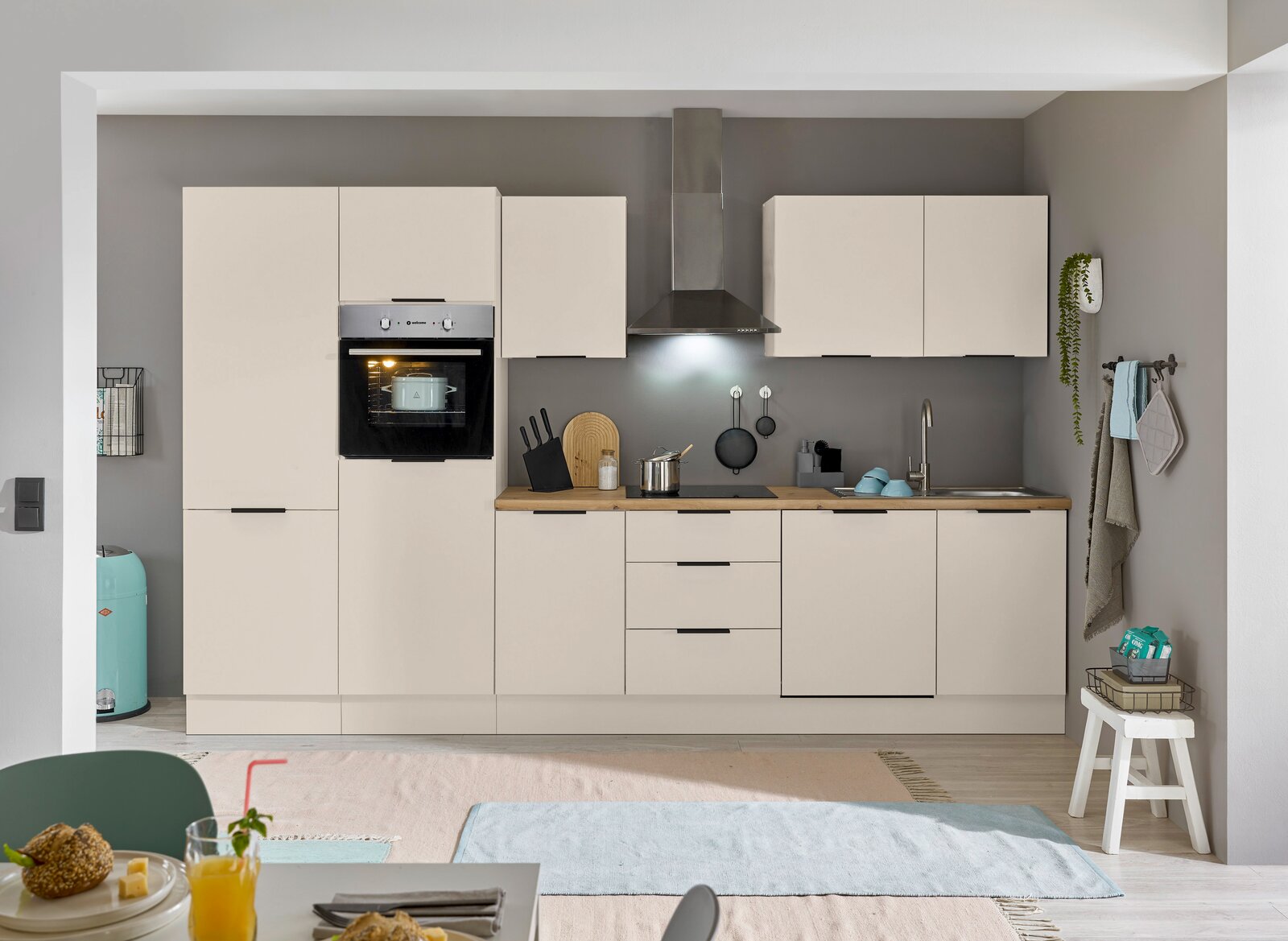 Moderne Küchenzeile in Cremeweiß mit eingebautem Backofen, Dunstabzugshaube und Spüle, frontal betrachtet.