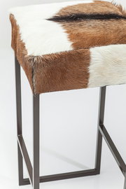 Hocker mit braun-weißer Felloberfläche und Metallgestell, seitliche Perspektive